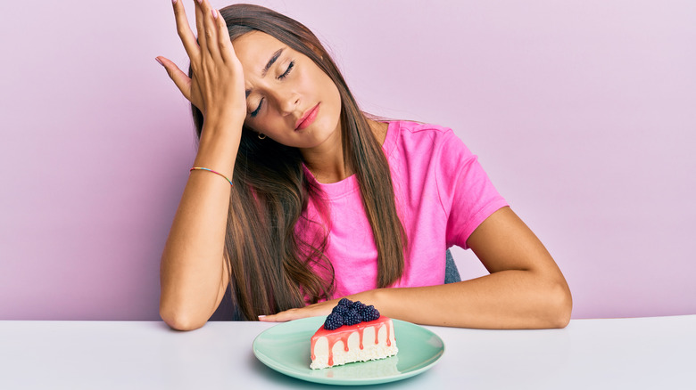 Stressed woman with cheesecake slice