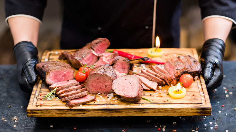 A chef holding grilled beef meat at a steakhouse