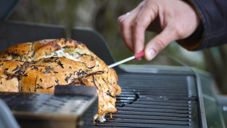 Hand probing meat in smoker