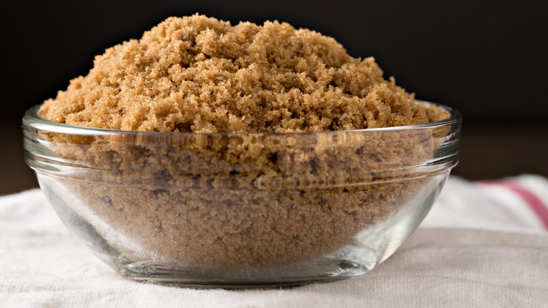 close up of glass bowl of brown sugar on a white towel