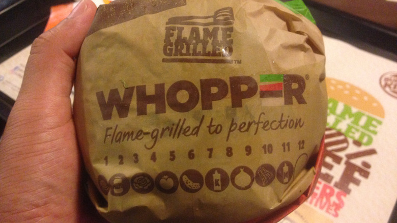 A wrapped Burger King Whopper in someone's hand