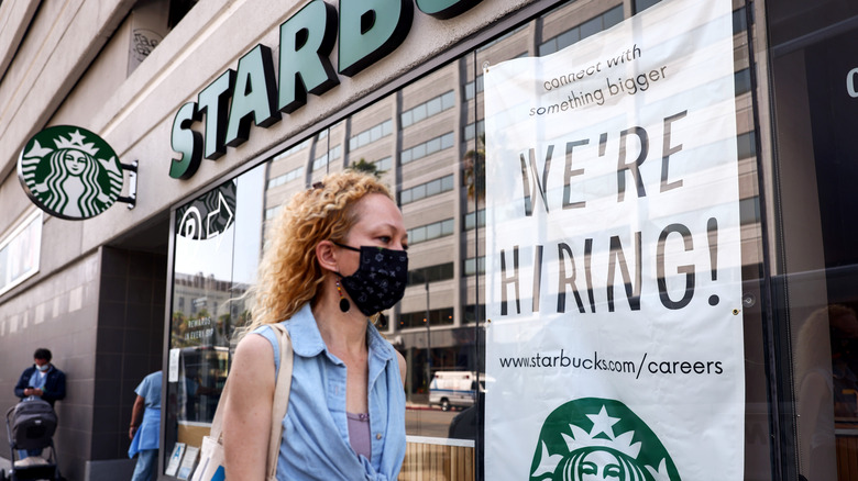 Woman passes Starbucks Hiring Sign