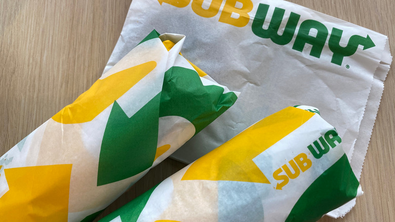 Wrapped subway sandwiches on brown wood