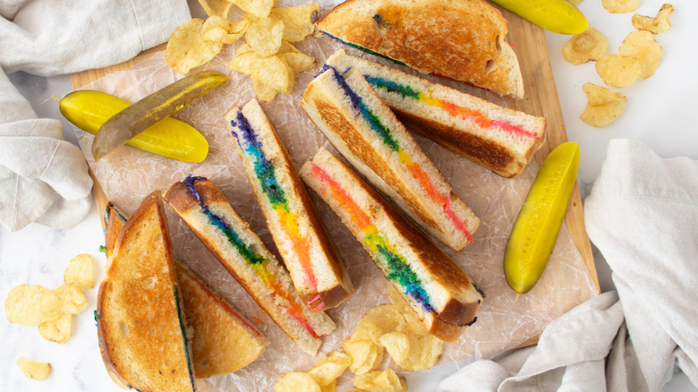 colorful rainbow grilled cheese sandwich halves with pickle spears and chips