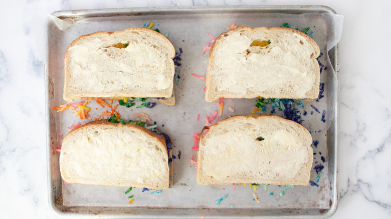 four sandwiches with colorful shredded cheese