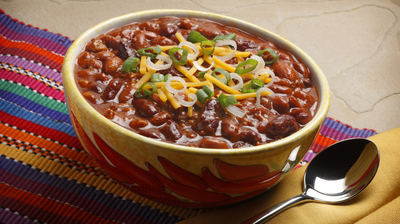 a bowl of chili with garnish and cheese shreds