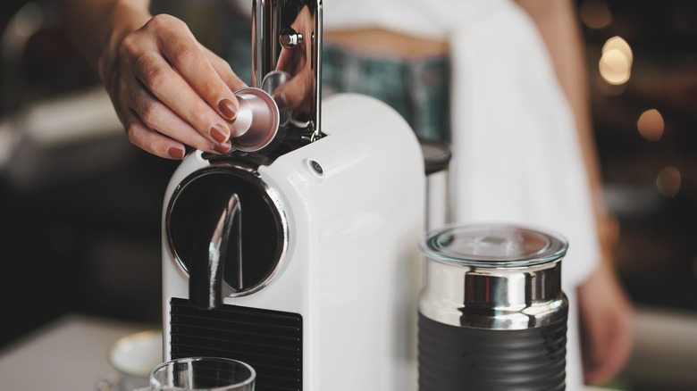 Women putting capsules in an espresso machine 