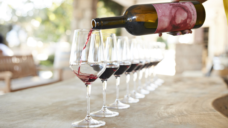 Hand pouring red wine into glasses