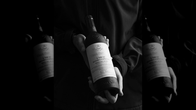 Hands holding wine bottle in black and white