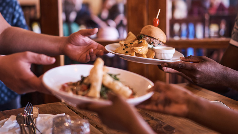 hands grabbing for plates of food