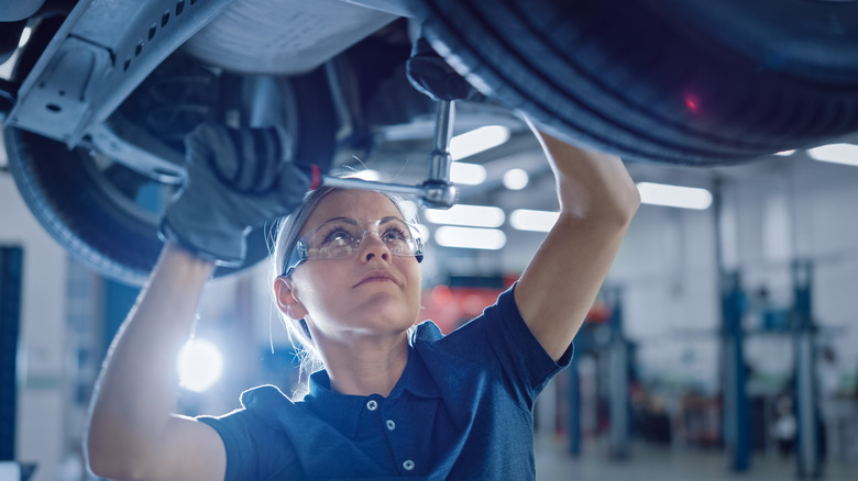 Female mechanic working under a car.