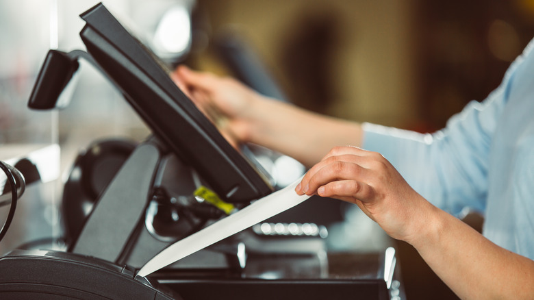 Cashier pulling receipt at register.