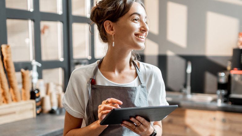 Happy barista smiling with tablet