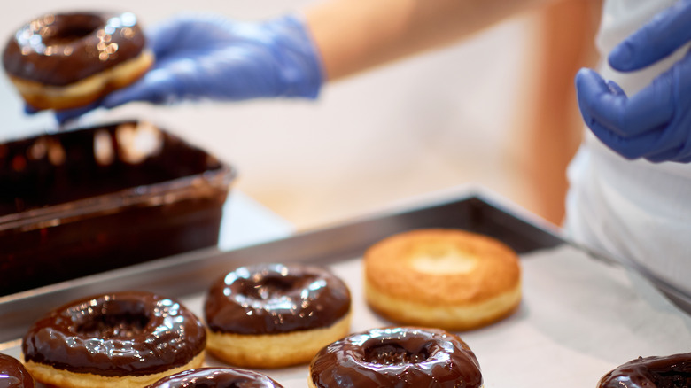 Baker dipping doughnuts in chocolate