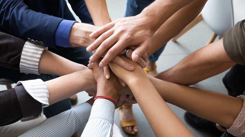 Employee hands stacked in team huddle