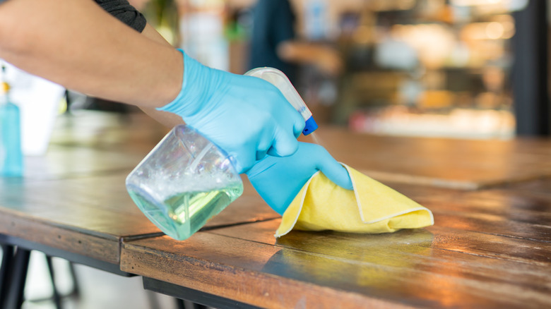 gloved man sanitizing restaurant table