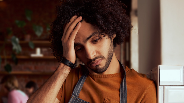 sad waiter holding head