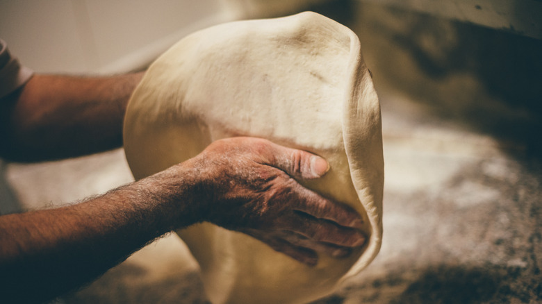 person stretching pizza dough