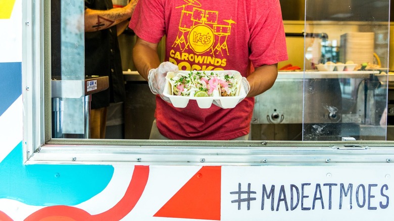 man holding tacos at window