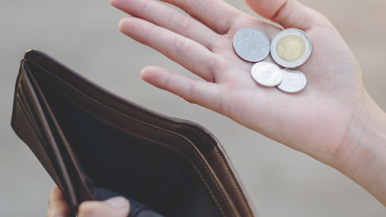 holding coins and empty wallet