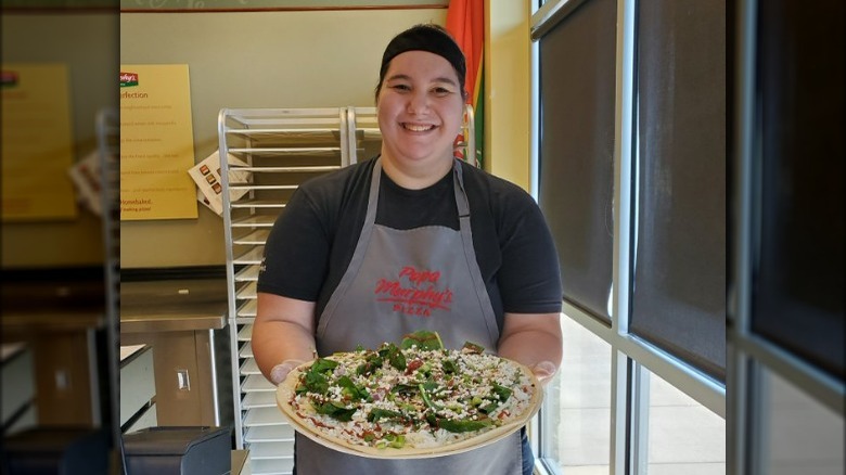 A Papa Murphy's employee holding a pizza