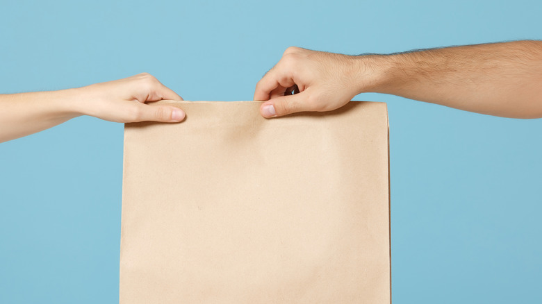 Two hands holding brown bag