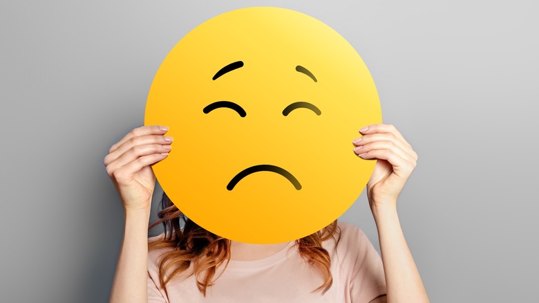 Person with unhappy emoji face.