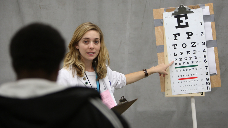 A woman points to an eye chart for a patient.