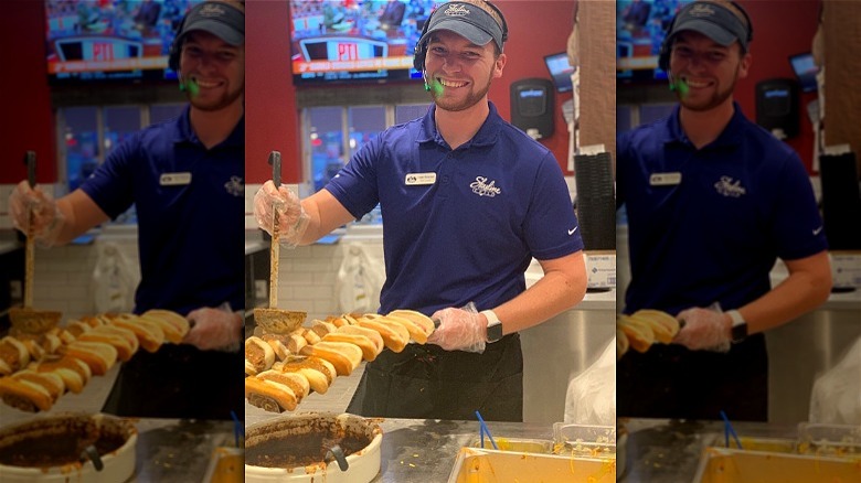 Restaurant worker ladling chili on to hot dogs