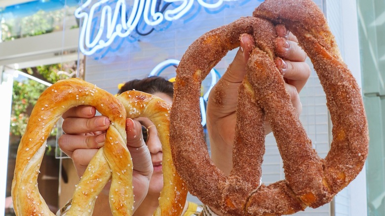 Woman holding two soft pretzels