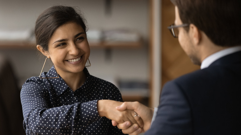 smiling woman shaking man's hand