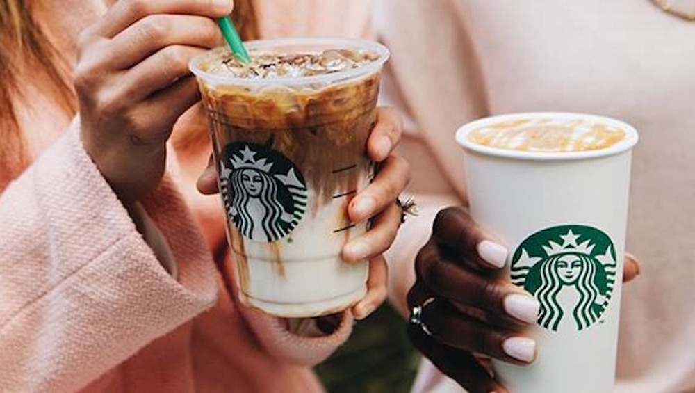 Two people holding Starbucks cups