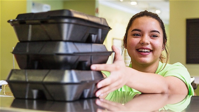 Employee smiling and holding take out containers