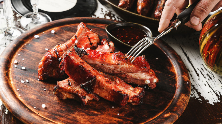 Person poking plated spare ribs with fork