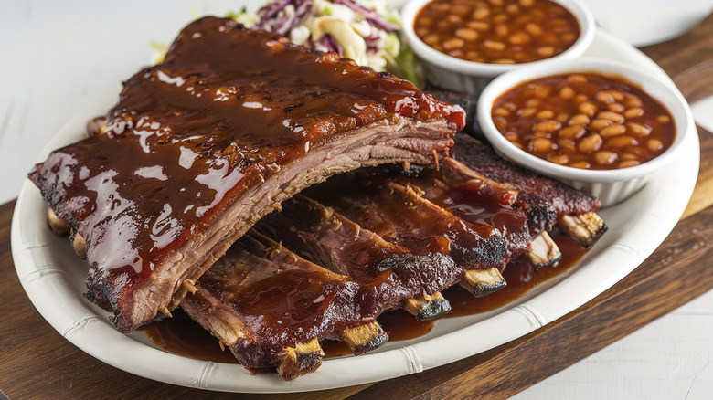 Barbecue ribs on white plate with beans and slaw