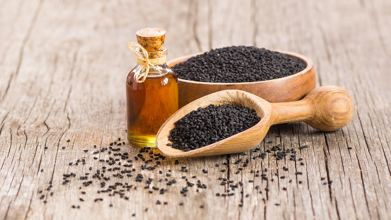 Nigella seeds in scooper on wood table