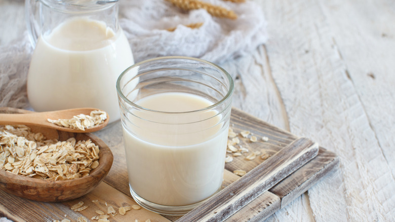 Glass of oat milk on a tray with oats