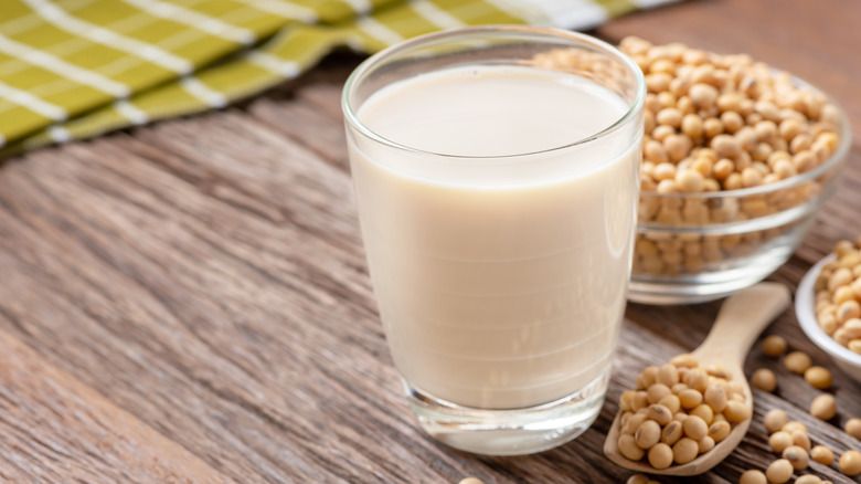 A glass of soy milk with soybeans in the background