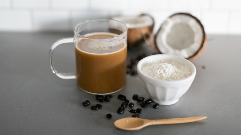 A cup of coffee with a bowl of creamer and coconuts