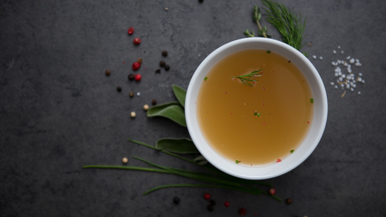 Vegetable broth in white bowl on marble slab