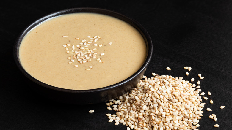 Tahini paste with sesame seeds in black bowl