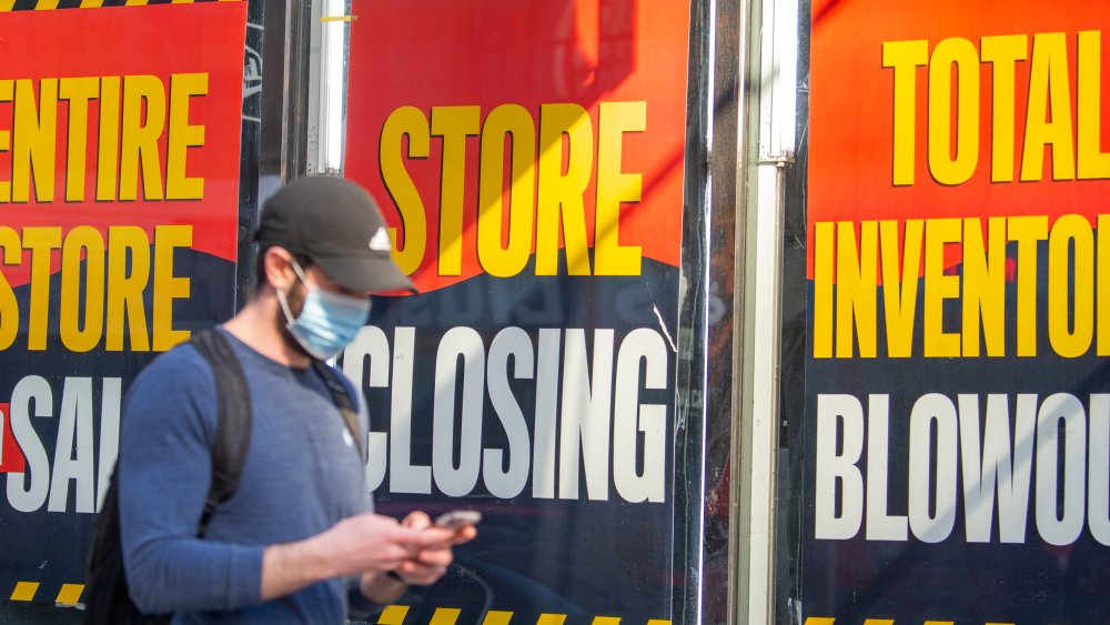Man walking past a 'going out of business' sign
