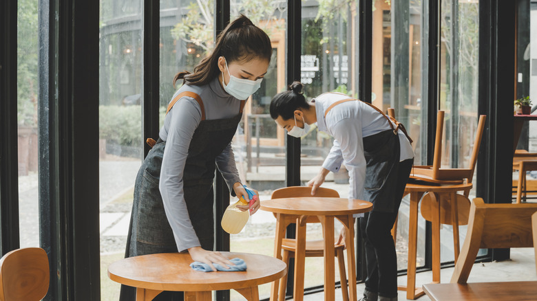 Restaurant staff wearing masks and cleaning tables