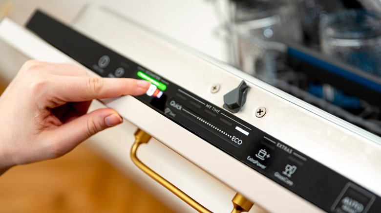 Woman pressing buttons on a dishwasher 