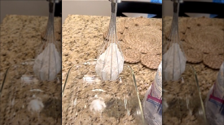 whisk holding flour above dish