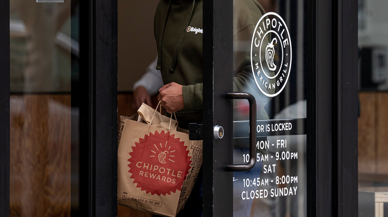 man walking out of chipotle with bag