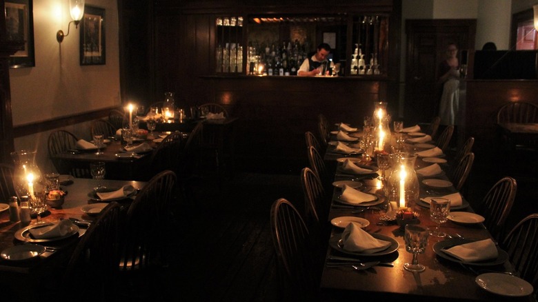 Candlelit dining room with bar and bartender in background