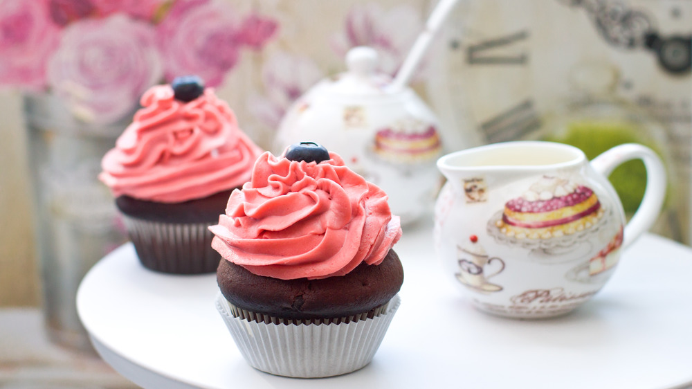 Strawberry cream cheese-frosted cupcakes with teapot