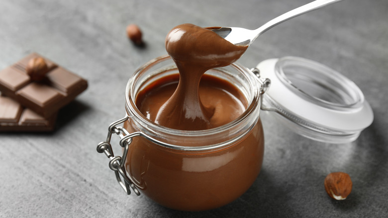 Chocolate sauce in a jar with a spoon dripping over it