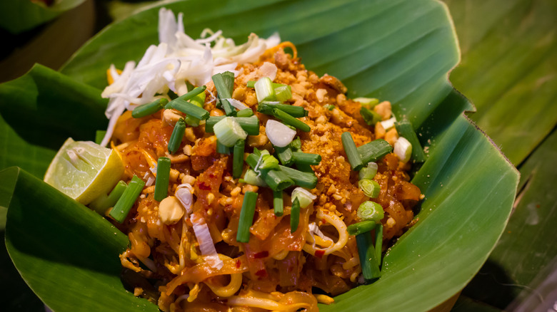 Paid Thai dish with green onions in banana leaf bowl